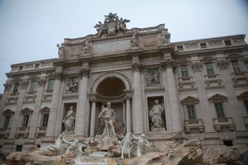 Fototapeta na wymiar Large Trevi Fountain adorns the exterior of a modern building, its features illuminated by the sun