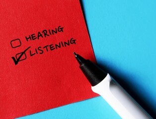 Red note with checkbox HEARING and LISTENING, concept of choose listening than just hearing, pay...
