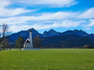 St Coloman's church building in greenery field surrounded by mountains