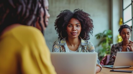 Young creative African American female businesswomen looking camera working with 3 stylists partnership woman in casual dress, sitting in workplace modern office, technology laptop computer on table