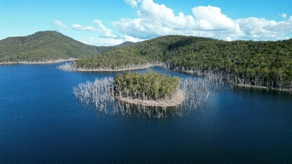 Naklejka premium Scenic aerial view of a tranquil lake surrounded by lush green hills, creating a tranquil atmosphere