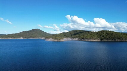 Obraz premium Scenic aerial view of a tranquil lake surrounded by lush green hills, creating a tranquil atmosphere