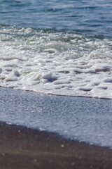 Vertical shot of a beach during the daytime with the waves washing up to the sandy shoreline