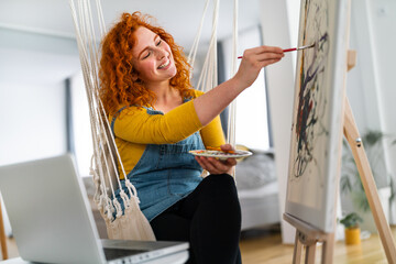 Happy and relaxed young woman enjoying her free time at home, expressing her creativity and...