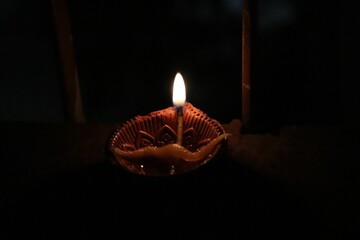 Black background illuminated by a bright yellow candle in the darkness of the night
