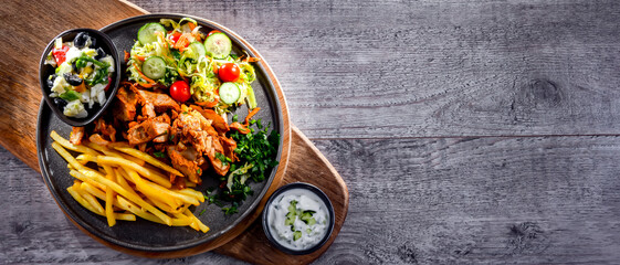 Kebab served with french fries, vegetable salad and tzatziki