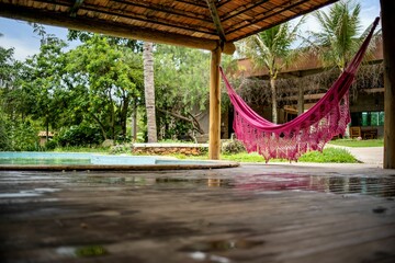 a hammock hanging over a wooden deck by a pool
