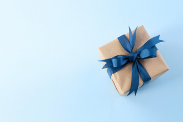 Present box with blue ribbon and bow top view on empty space blue background. Father's day gift