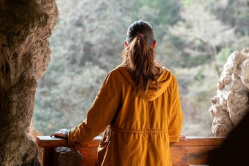 Young woman standing in a cave overlooking a landscape