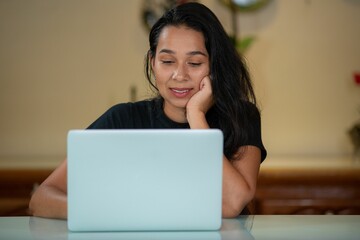 a woman sitting at a table with a laptop computer in front of her