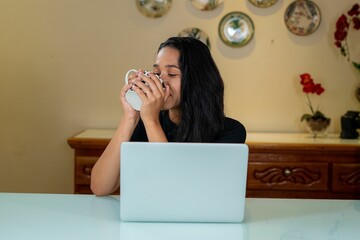 a woman is enjoying coffee at the table with her laptop