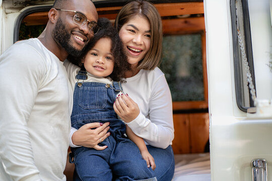 Multiracial family having fun laughing together. Multiethnic father and biracial daughter enjoying outside. Dad and Asian mom happy playing with cheerful kid girl in backyard. Diversity family bonding
