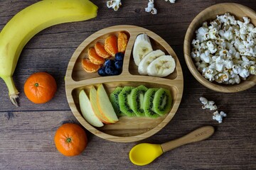 Wooden table is filled with a variety of colorful fruits and popcorn
