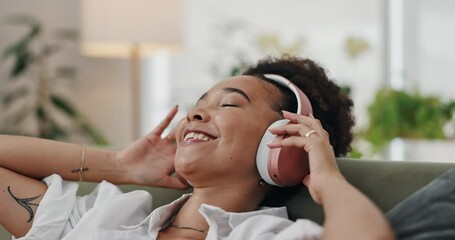 Happy woman, headphones and listening to music on sofa for podcast in living room at home. Calm young female person in relax or enjoying audio streaming, sound or song playlist with headset at house