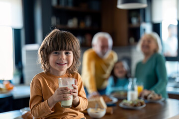 Smiling boy drinking milk and leaving a white moustache on his face.