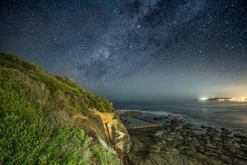 Rocky shoreline illuminated by the bright stars in the night sky