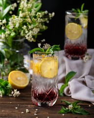 Glass of refreshing lemonade garnished with fresh lemons and mint leaves, set on a wooden table