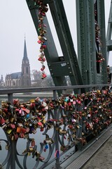 many locks are attached to a bridge over water near a city