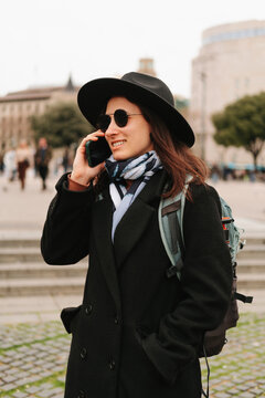 Vertical shot of a young tourist woman talking on the phone while walking.