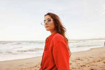 Smiling Woman in Sunglasses, Enjoying the Ocean's Freedom at Sunset: A Colourful Portrait in Trendy Clothing