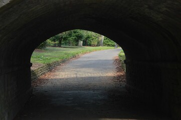 Eerily lit tunnel with a road that leads to a lush green park