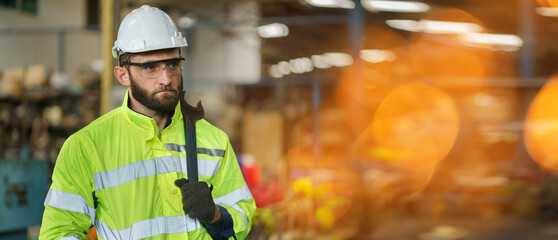 Portrait of caucasian industrial worker beard man with helmet crossed arms holding wrench in...