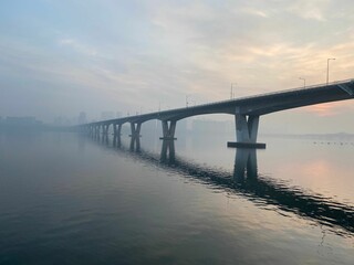 Scenic view of a foggy bridge spanning over a tranquil body of water. Seoul, South Korea.
