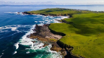Aerial view of sea waves against the green coastline