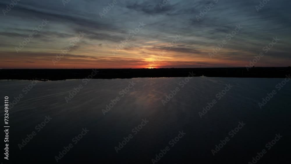 Canvas Prints Landscape scene of gray body of water with silhouette shore with sunset colorful sky