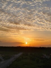 Aerial view of a stunning sunset view of the road with a sky filled with billowing clouds