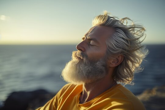 Peaceful Shoreline: Handsome Man in Meditation, Gray Hair and Beard Gently Swaying by the Ocean