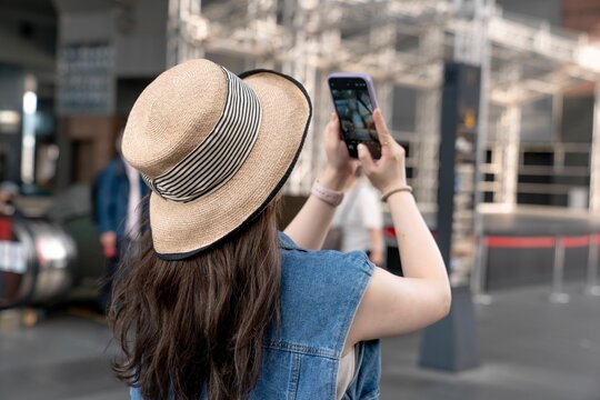 Young female in a straw hat, taking photos with her phone