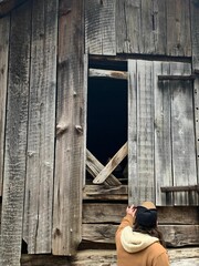 Person standing next to an old, rustic cabin