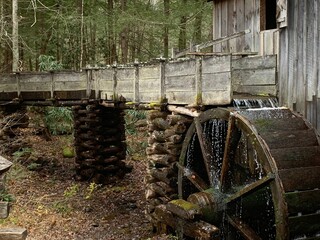 Old wooden water wheel in motion, with the water running off of it