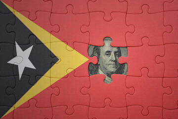 puzzle with the national flag of east timor and usa dollar banknote. finance concept