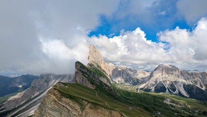 Vast mountain range stretching across the horizon, framed by the cloudy sky above in Seceda, Italy.
