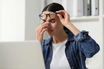 Woman suffering from headache at workplace in office