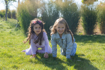 Fototapeta premium Two Little Girls Having Fun in Park on a Green Lawn. Friendship, relation, childhood, leisure and people concept