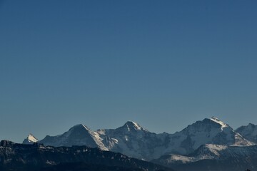 a plane flying over a snow covered mountain side line under the blue sky