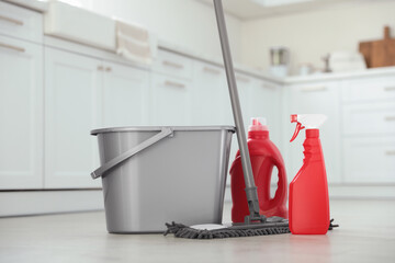 Mop, detergents and plastic bucket in kitchen. Cleaning supplies