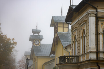 Deptak Krynicki w porannych mgłach jesienią. Widok na budynek.