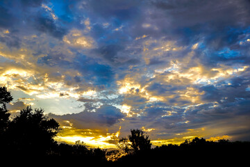 beautiful clouds over a dark forest as the sun sets in a cloudy sky, Missouri Sunset
