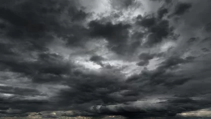 Fotobehang dark dramatic sky with black stormy clouds before rain or snow as abstract background, extreme weather, the sun shines through the clouds, high contrast photo © soleg