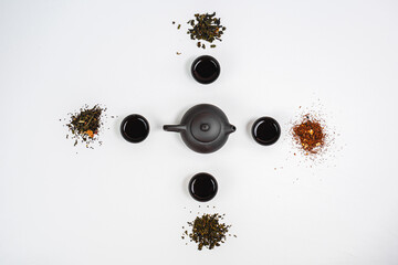 Black teapot and cups with bamboo leaves on a tray. Traditional tea ceremony. 
View from above. Various types of tea.