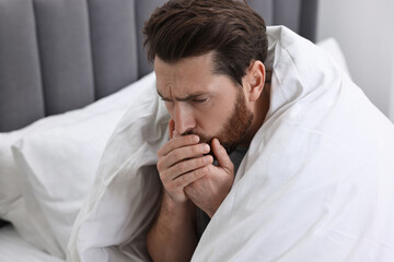 Sick man coughing on bed. Cold symptoms
