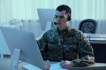 Military service. Young soldier in headphones working at table in office
