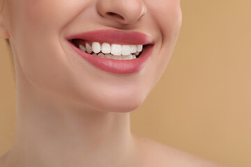 Young woman with beautiful smile on beige background, closeup