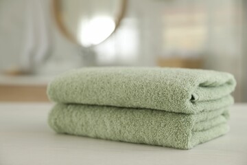 Fototapeta na wymiar Stack of clean towels on white wooden table in bathroom