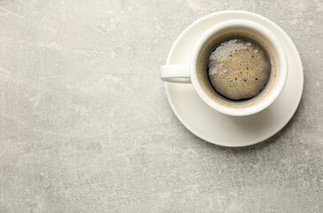 Cup of aromatic coffee on light grey table, top view. Space for text