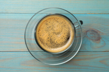 Cup of aromatic coffee on light blue wooden table, top view